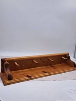Full view of wooden coat rack with shelf and four pegs