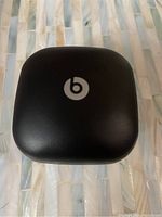 Closed black matte Beats charging case with white logo on top.