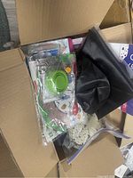 View inside box showing crafting supplies, fabric, containers, and paper materials closely packed.