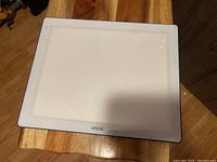 Full top view of the Cricut Bright Pad displaying the entire translucent surface and wooden table beneath.