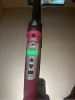 Close-up of the curler's control panel featuring an illuminated digital display showing temperature and buttons for adjustment.