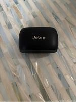 Closed black Jabra charging case shown from the top on a textured white surface.