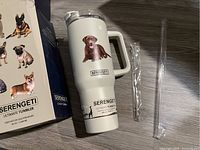 Serengeti Ultimate Tumbler, white with brown Labrador images on front and back, lying on flat surface with its box and accessories visible.