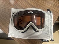 Front view of the Smith snowboarding goggles on top of a white carrying pouch on a wooden surface.