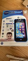 Front of the box showing Kidibuzz branding and kid-friendly features such as video chat, messaging, fun filters, and safe device design.