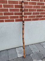 Full length view of wooden hiking stick showing natural wood texture and length.