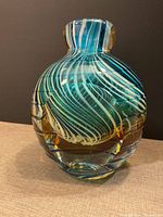 Front view of the glass art sculpture showing blue and white swirl patterns with amber accents.