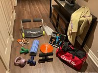 Wide shot of all exercise and fitness items including Smart Wonder Core, various hand weights, foam roller, exercise towel, balance disc, wrist or ankle weights, cloth, and gym bag.