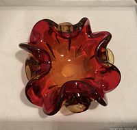 Top-down view of the glass art dish showing vibrant red color and flowing curved edges