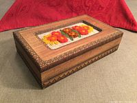 Photo of handcrafted wooden keepsake box closed, showing wood grain, carved edges, and wool floral design on lid.