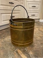 Photo showing full view of the brass planter with wrought iron handle on kitchen floor, highlighting the size and handle design.