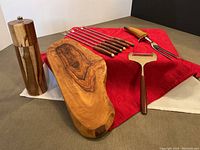 Photo showing olive wood cutting board, wooden Uppwell rock salt mill, six vintage fondue forks, one large fork, and stainless steel cheese shaver.