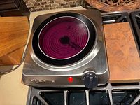 Top view of OVENTE infrared burner with the heating element on and glowing red under the ceramic glass surface, showing operational status and condition of the cooktop.