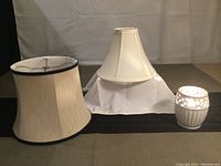 Two lamp shades and a white ceramic night light displayed together on a surface under bright lighting, showing overall clean condition and details of each item.