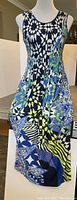 Front view of sleeveless full-length dress with geometric multicolor print on mannequin.