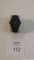 Black and blue Casio G-Shock watch with rubber band shown front view on white background with auction tag.