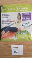 Front packaging of the Gaiam CorePlus Reformer Resistance Band Kit showing branding, workout benefit claims, and image of a woman using the band.
