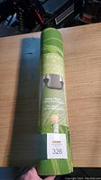 Rolled up Gaiam Premium Yoga Mat with label visible describing extra thick cushioning, sea grass color design