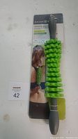 Front view of Gaiam Restore Adjustable Massage Roller in original packaging showing green massage segments and gray handles.