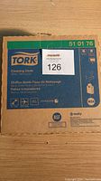Front view of a cardboard box of Tork cleaning cloths in unopened condition, labeled with product number 51 01 76 and white cleaning cloths text in multiple languages.