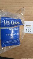 Front view of Uline industrial strapping tape roll in packaging with blue branding label.