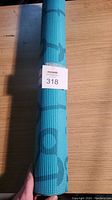 Photo of a rolled-up green yoga mat with a lot label attached.