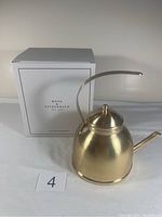 Brushed gold kettle next to its original box labeled Rose & Fitzgerald