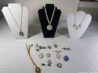 Full lot overview showing cameo necklaces on display busts and assorted rings, earrings, and brooches laid out on table