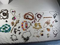 Full view of the costume jewellery lot showing necklaces, earrings, bracelets, and rings spread out on a surface.