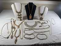 Photo of the entire assortment showing diverse necklace and bracelet styles in gold tone, some displayed on busts.