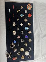 Full collection of 32 costume rings displayed on black tray showing a variety of designs including enamel, rhinestone, cameo, and floral.