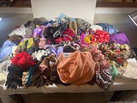 Photo showing an assortment of scarves, tams, hats, and gloves spread out on a table.