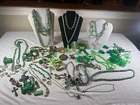 Overall table layout showing bulk of green jewelry items including necklaces, bracelets, rings, pins and accessories
