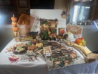 Wide view showing entire Thanksgiving lot including place mats, napkin rings, door hangings, and assorted decor items arranged on a white tablecloth.