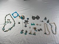 Full view of jewellery collection including necklaces, earrings, rings, bracelets, and pendants spread on a white surface.