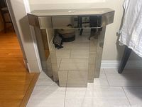 Front view of vintage Art Deco mirrored glass side table with single drawer, showing geometric mirrored panels and octagonal shape.