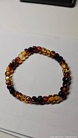 Photo showing the AAA Baltic amber stretch bracelet laid flat, displaying beads in multiple amber hues from golden to dark brown.