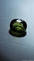 Front view of the oval cut natural forest green sapphire showing color and clarity with minor inclusion visible