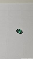 Oval cut natural Zambian emerald gemstone on neutral background, showing overall shape and size.