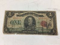Front side of a heavily worn 1923 Canadian one dollar banknote showing portrait of King George V and serial numbers.