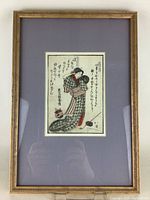 Framed antique Japanese woodblock print featuring a woman in traditional kimono with mat and frame.