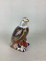 Front side of the detailed eagle sculpture showing gold and purple scales, golden beak, and decorative base