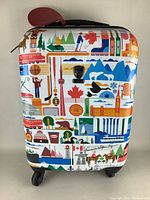 Front view of hard shell luggage with colorful Canada-themed graphics and four wheels