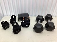 Nike wrist weights and two hex dumbbells displayed on white surface