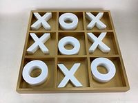 Front view of Tic Tac Toe board filled with large white X and O pieces, showing grid and game pieces clearly.