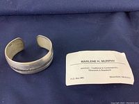 Sterling silver Navajo cuff bracelet laid on dark cloth next to a business card