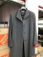 Full view of the dark gray full-length coat hanging on a hanger, showing the front with buttons and collar.