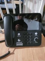 CaptionCall phone system showing handset, keypad, function buttons, volume knob, and caption display screen