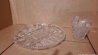 Photo showing divided clear lead crystal serving platter with intricate deco cut pattern alongside a glass container with cut design and handle.