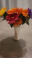 Front view of colorful artificial flowers in white vase